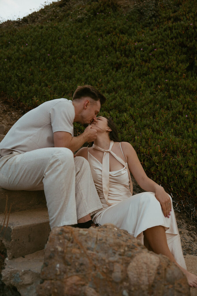A California couple shares a kiss along the shoreline of Pigeon Point Lighthouse during their bay area engagement photos