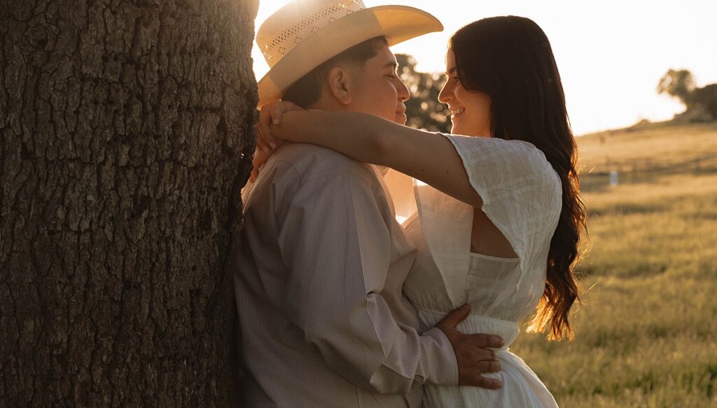 A couple embrace at golden hour for their playful farm engagement photos california