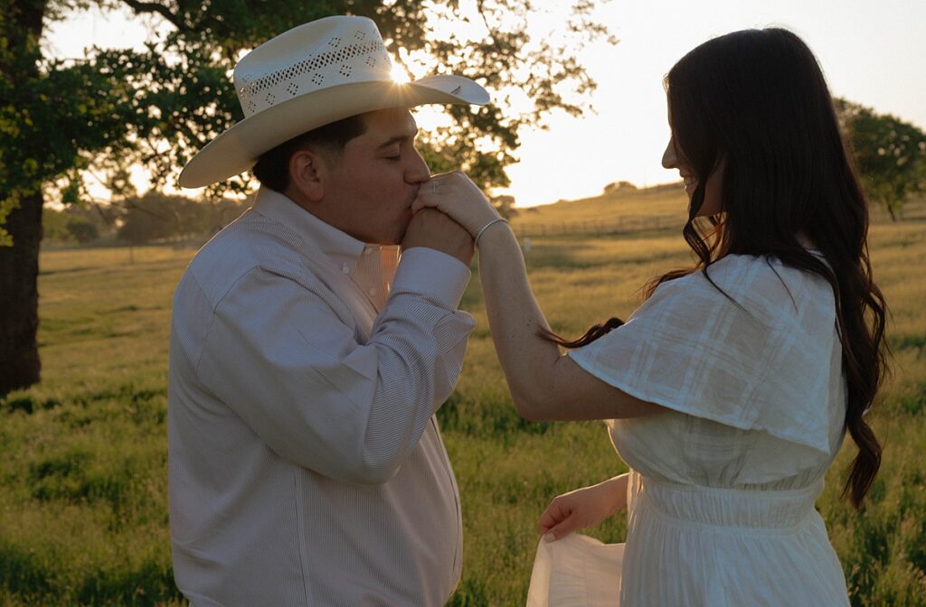 A man kisses his fiancée's hand during california wine country pictures to celebrate their engagement 