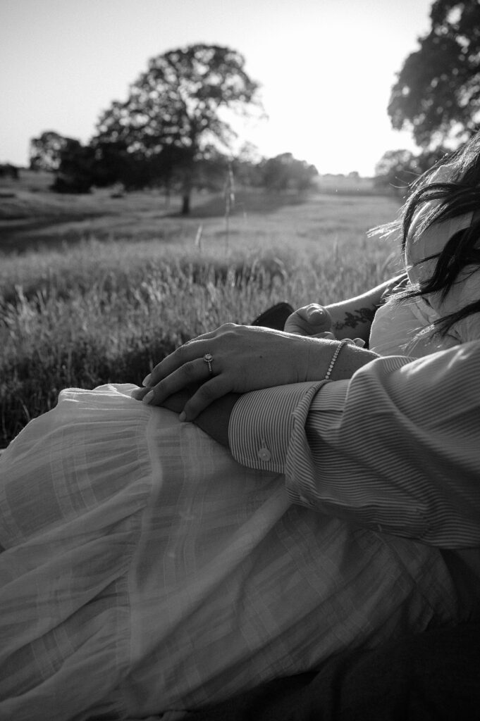 A black and white photo focuses on the engagement ring as a CA couple pose for photos with an amador county photographer