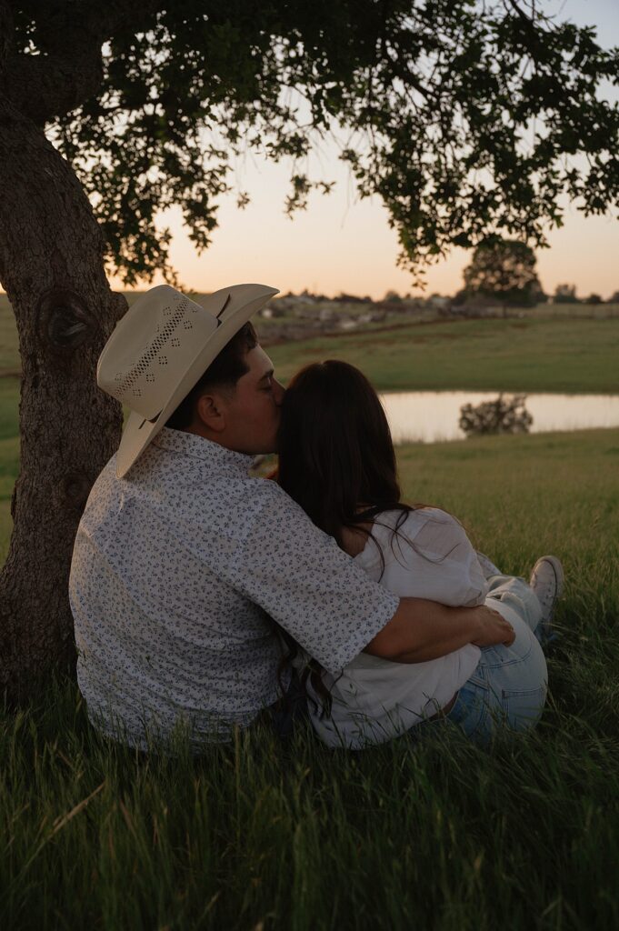 A man in a cowboy hat leans in to kiss his fiancee for a photo taken during engagment photos california 