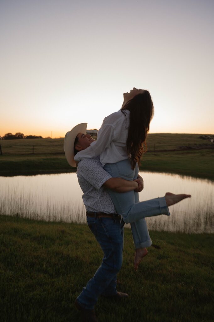 A man lifts his soon-to-be bride into the air at sunset during engagement photos with california engagement photographer