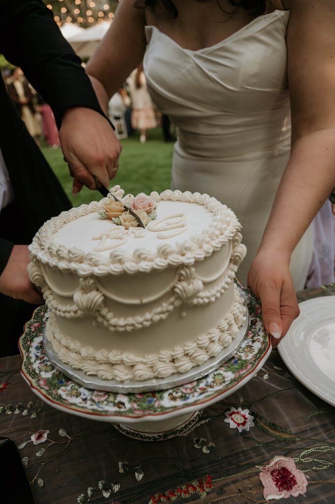 A close up photo of a bride & groom cutting the cake at their outdoor reception at a  sutter creek wedding venue