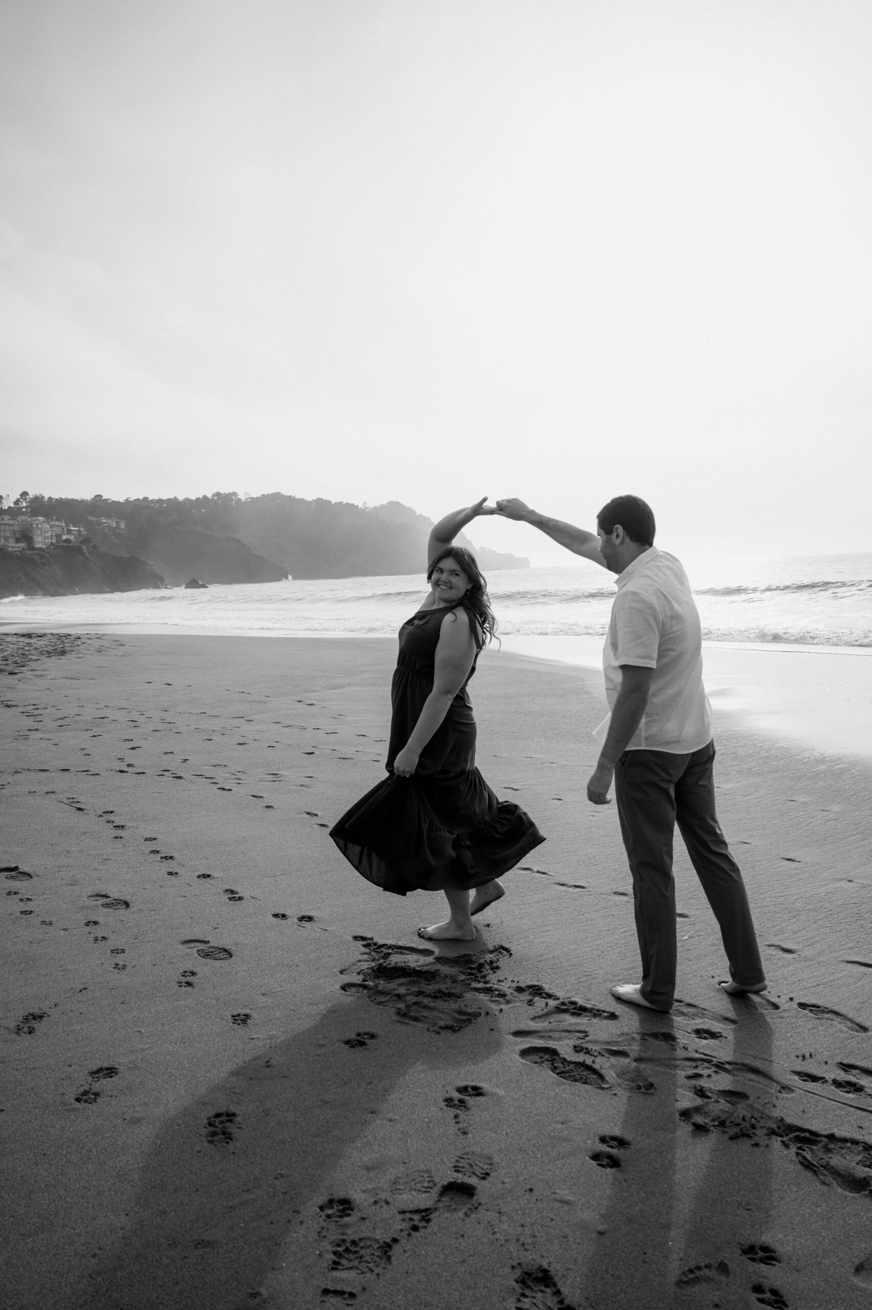 Newly engaged couple dances on the shoreline of beach in San Francisco during their engagement photos