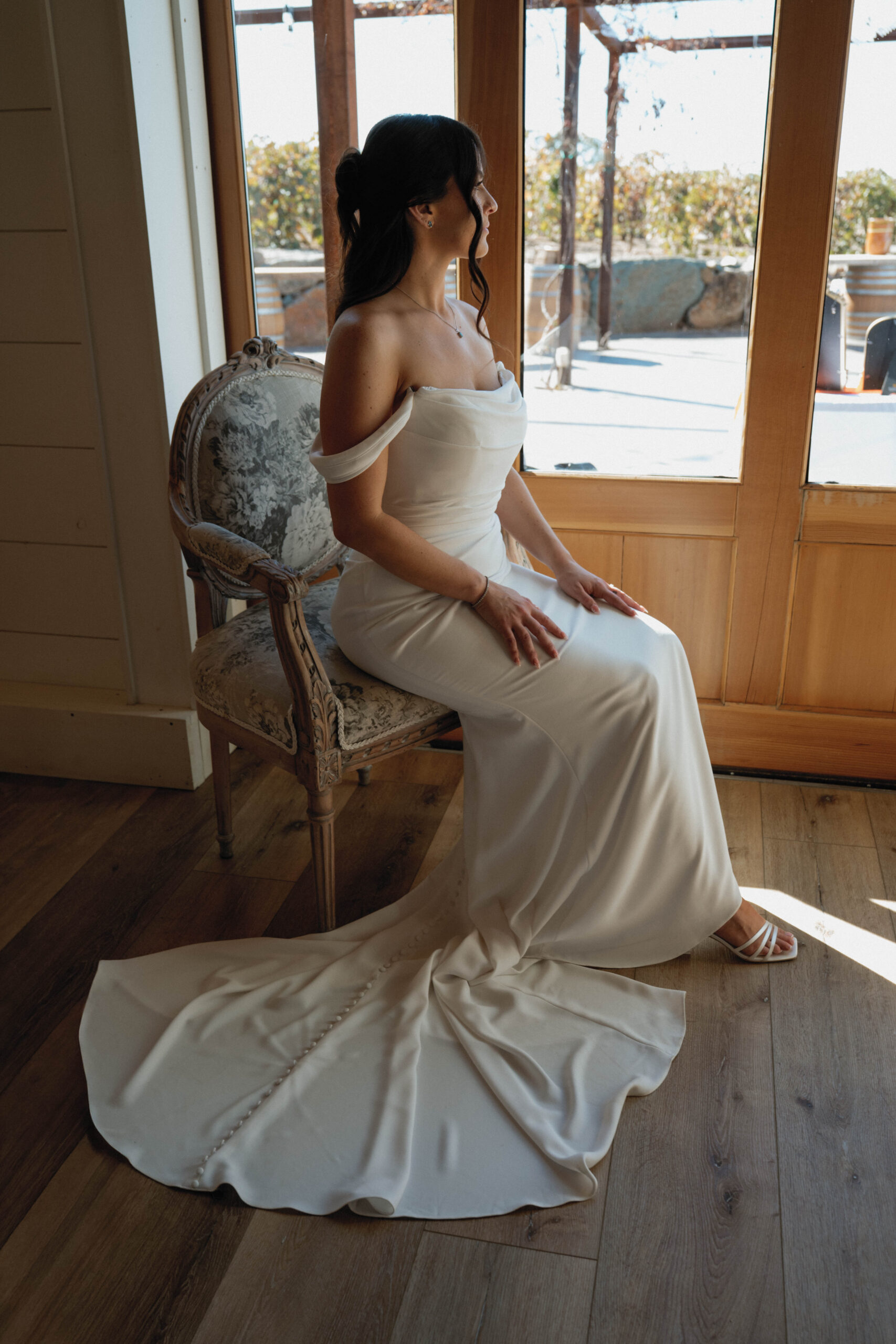 Bride poses elegantly with the natural daylight coming in through large windows during her portraits