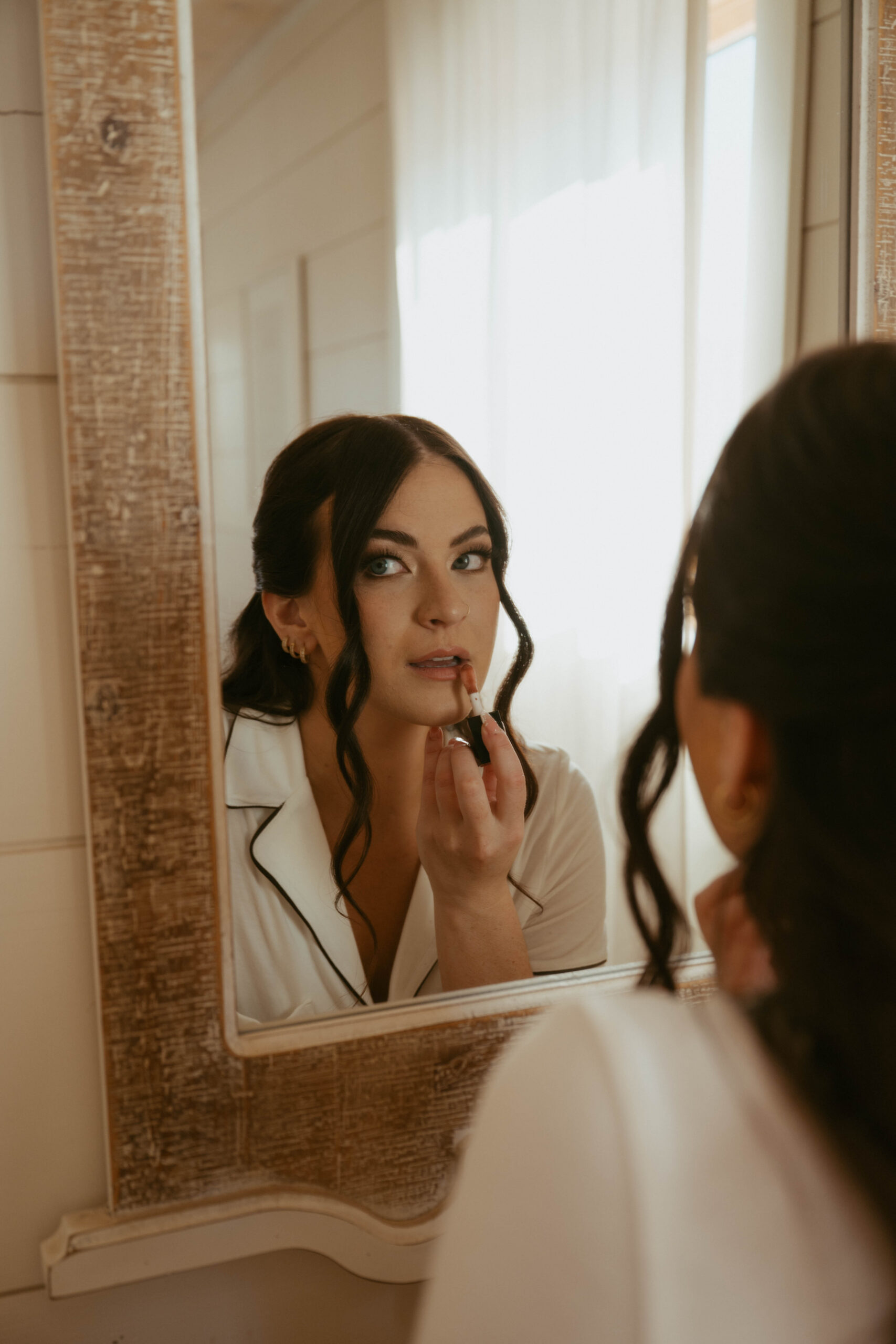 bride applies lipgloss as she prepares for her wedding day in Ione, California
