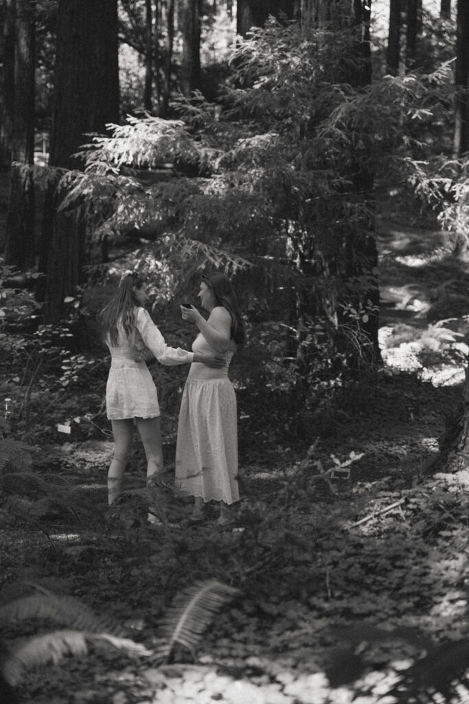 Black and white photo of a proposal moment captured from behind in the redwood forest