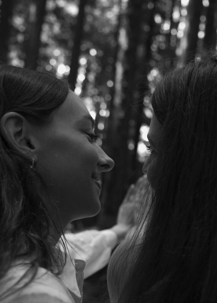 Tender black and white moment between a newly engaged couple in the forest